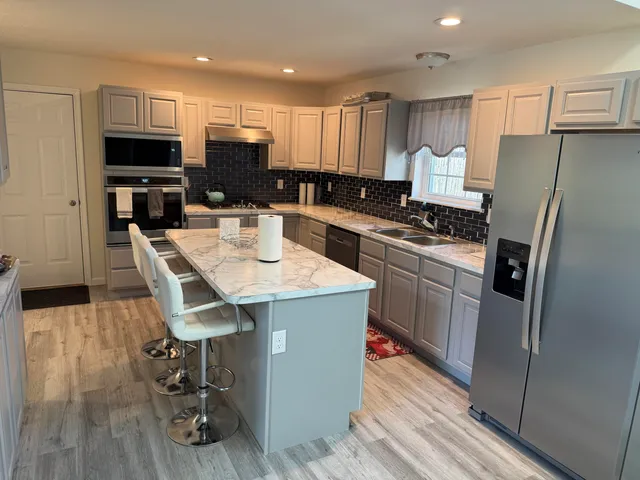 a kitchen with stainless steel appliances a stove a sink a microwave a refrigerator and cabinets