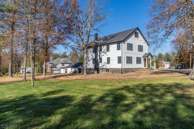 a view of a white house in front of a big yard with large trees
