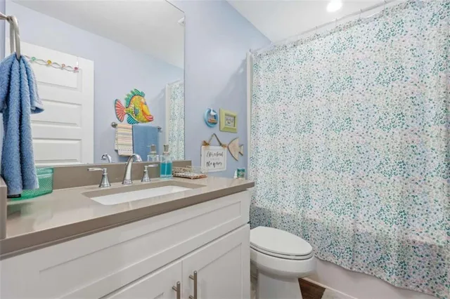 a bathroom with a granite countertop toilet and a sink