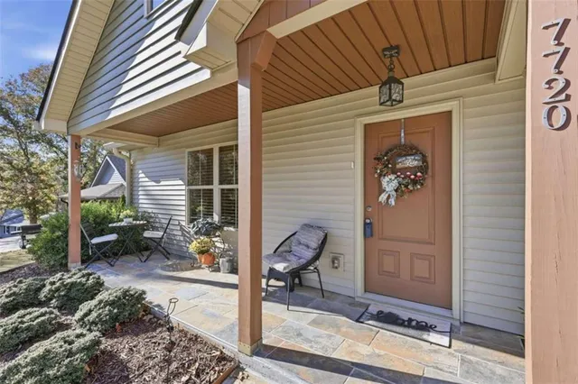 a view of a door of the house with a chairs and table in a patio
