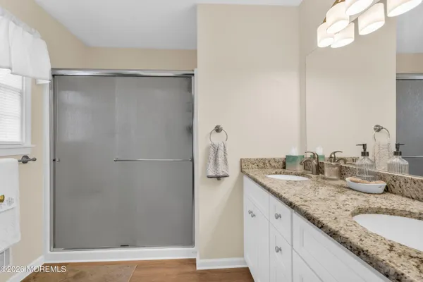 a bathroom with a granite countertop shower sink and mirror