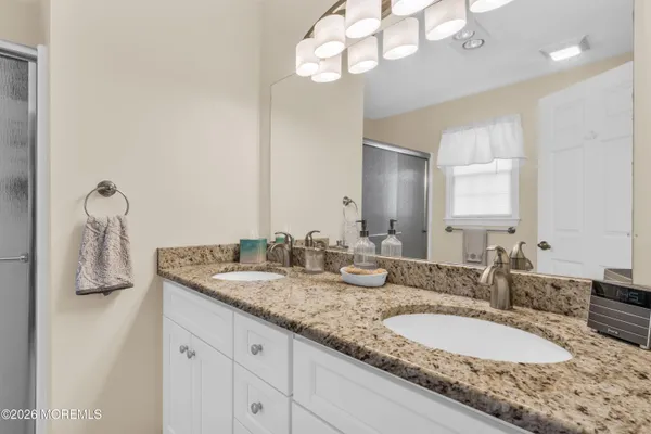 a bathroom with a granite countertop double vanity and a mirror