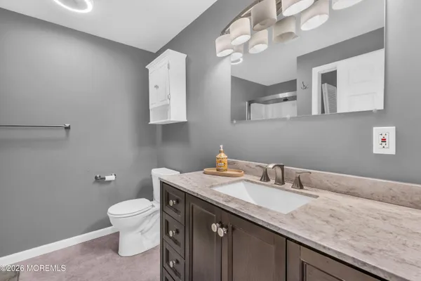 a bathroom with a granite countertop sink a toilet and a mirror