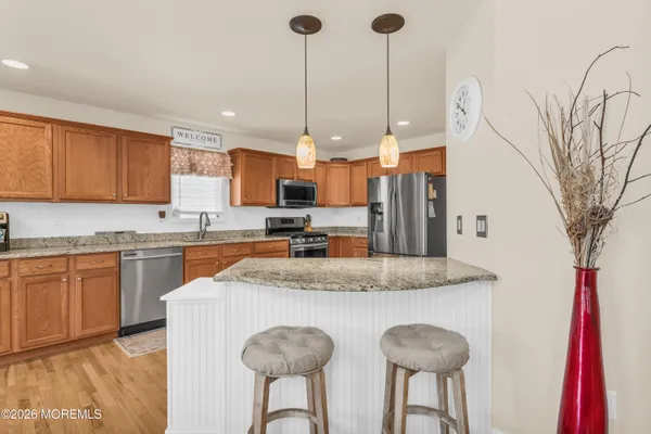 a kitchen with stainless steel appliances granite countertop a sink a stove a refrigerator a center island and a refrigerator