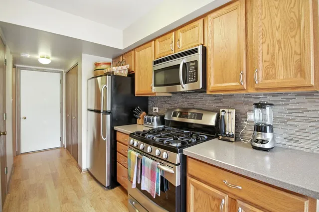 a kitchen with stainless steel appliances granite countertop a refrigerator a stove and a sink with wooden floor