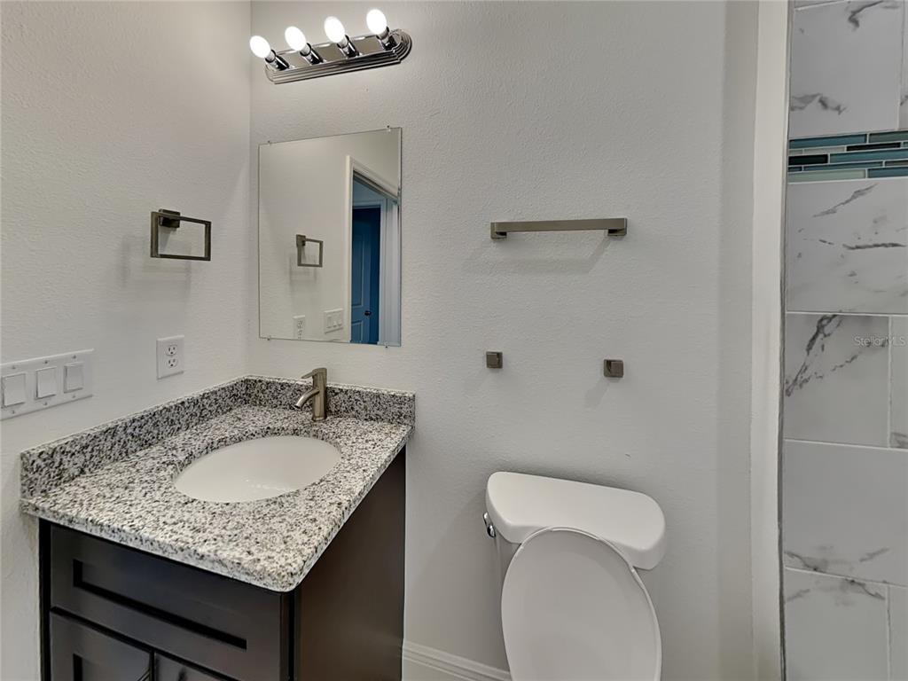 8809 North Sandree Drive Citrus Springs, FL 34434 - Photo 14 of 16 a bathroom with a granite countertop sink a toilet and a mirror