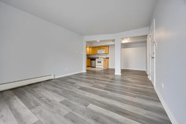 a view of empty room with wooden floor and fan