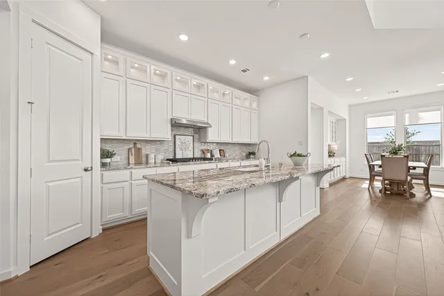 a kitchen with white cabinets sink and stove