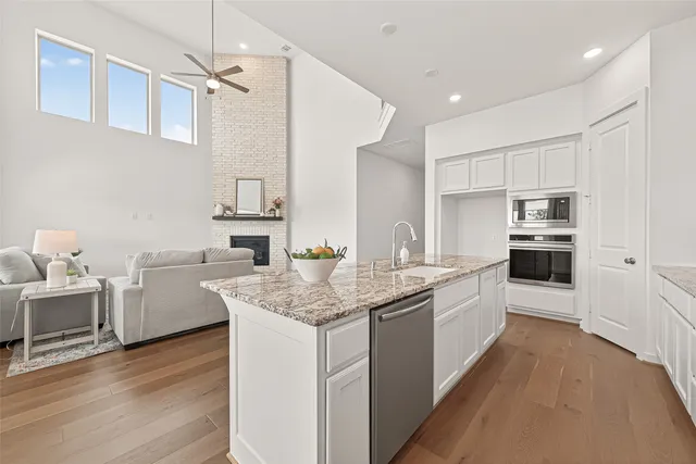a kitchen with white cabinets appliances and wooden floor