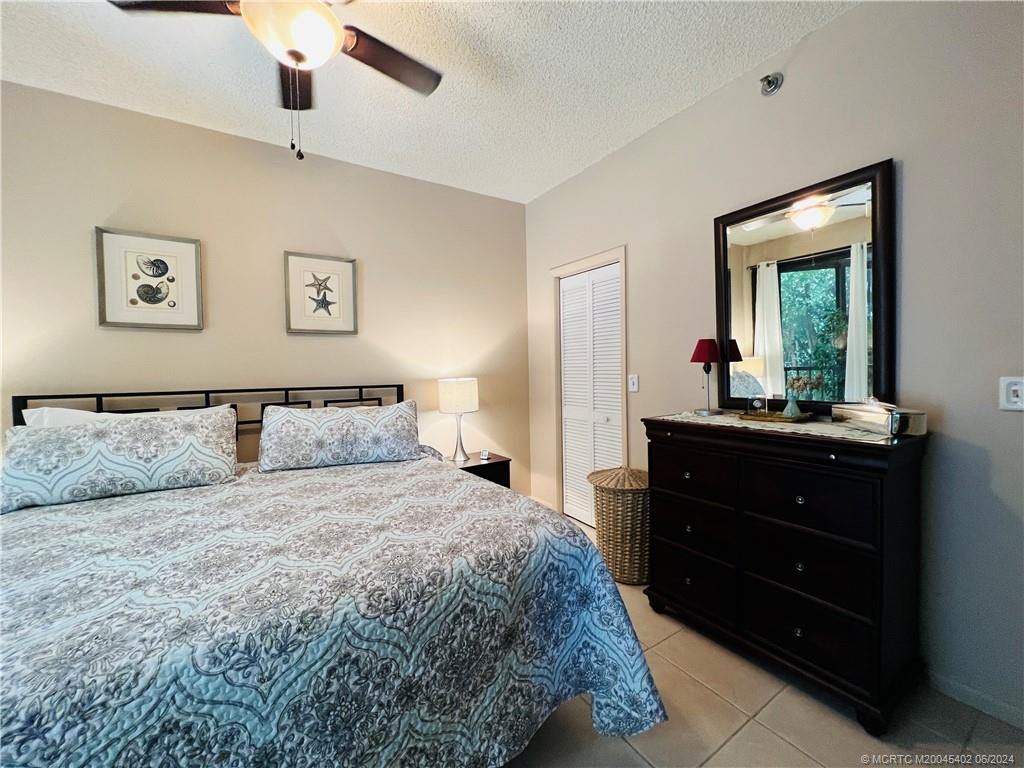 221 Northeast Plantation Road, Unit 215 Stuart, FL 34996 - Photo 32 of 83 a bedroom with a bed and a mirror on dresser