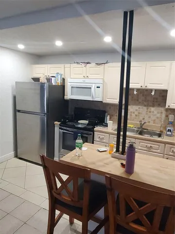 a kitchen with a table chairs refrigerator and microwave