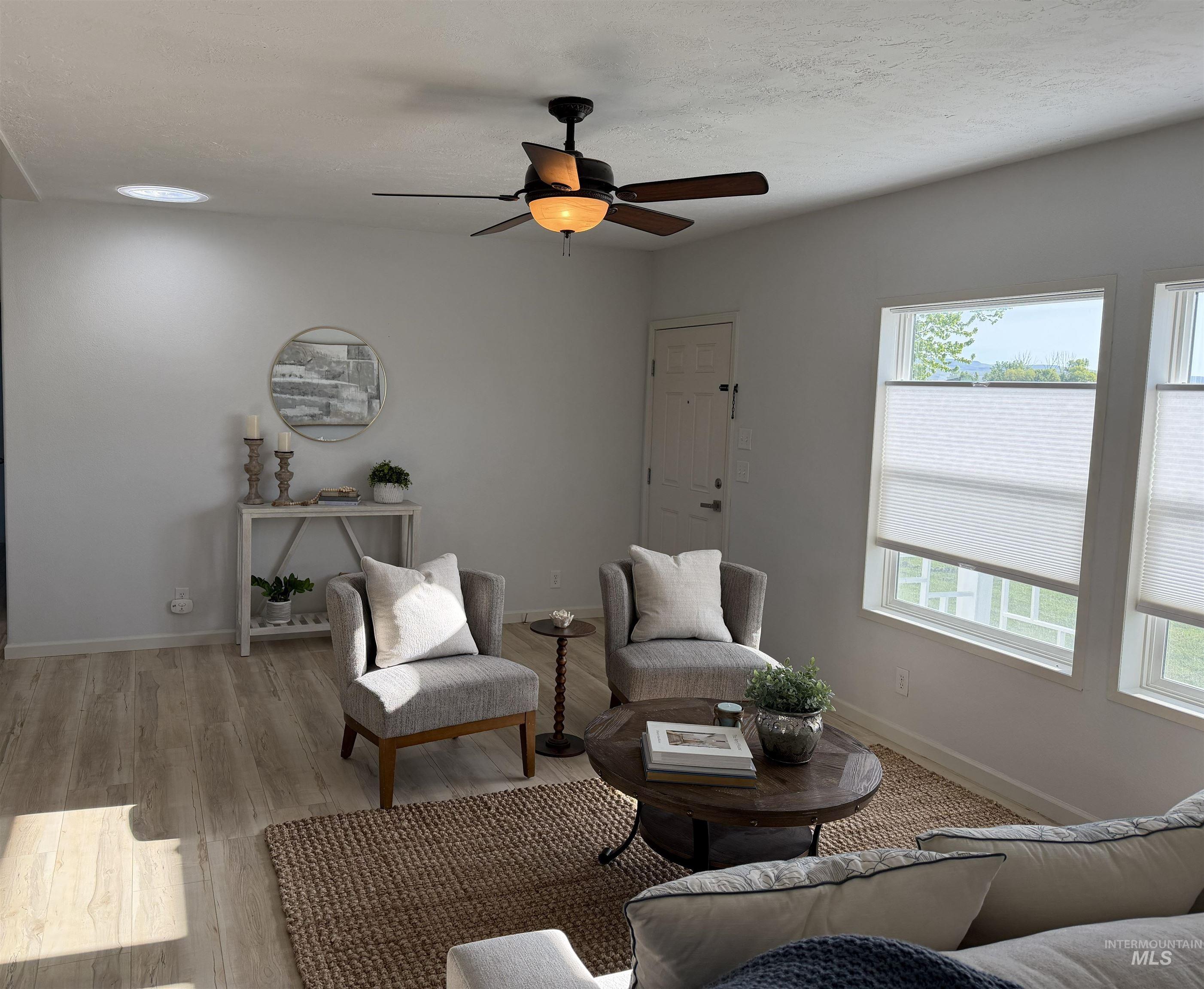 875 Eaton Road Weiser, ID 83672 - Photo 11 of 30 Living area featuring wood-finish flooring, a ceiling fan with integrated lighting, a tubular skylight, and multiple windows with cellular shades