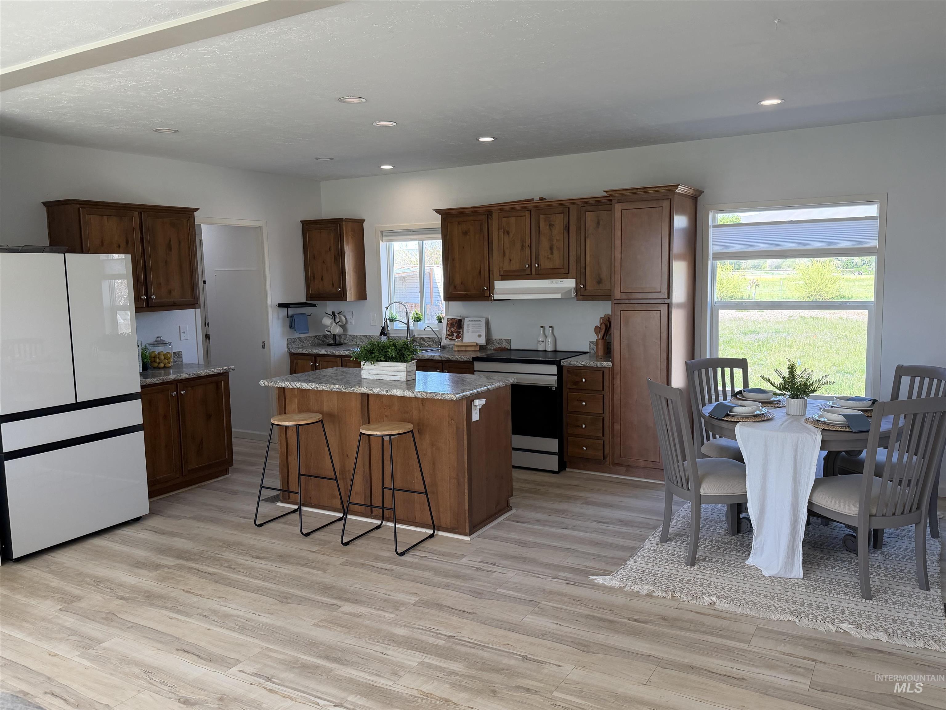 875 Eaton Road Weiser, ID 83672 - Photo 12 of 30 Open-concept kitchen and dining area featuring wood-finish flooring, recessed lighting, wood cabinetry, stone countertops, and a central island