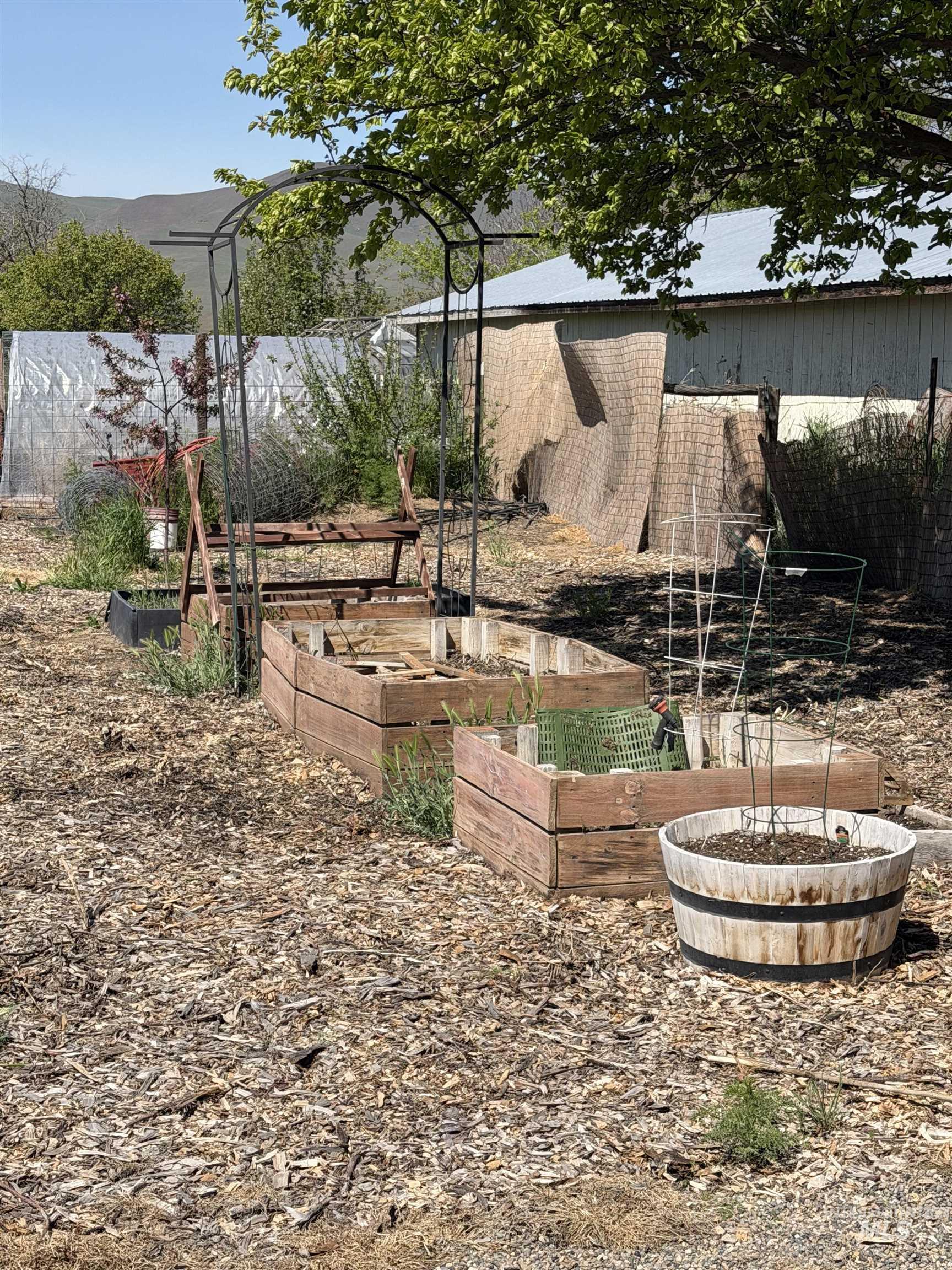 875 Eaton Road Weiser, ID 83672 - Photo 24 of 30 Garden area featuring two raised wood garden beds, an arched metal trellis, a wood barrel planter, and ground covered in wood chips