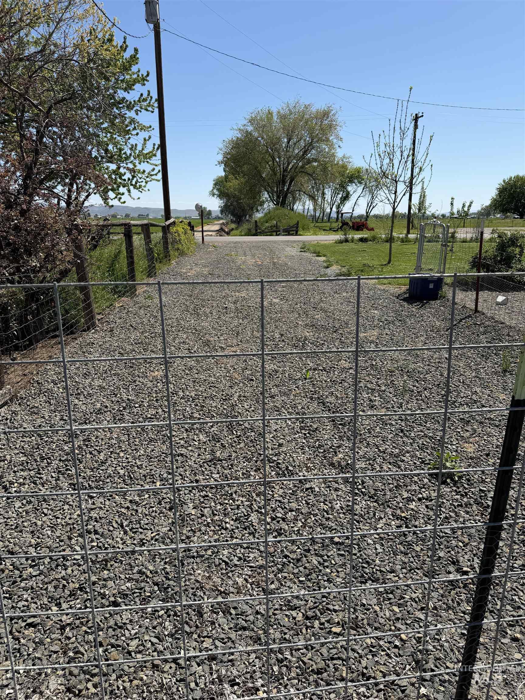 875 Eaton Road Weiser, ID 83672 - Photo 7 of 30 Gravel driveway entrance with wire fencing and mature trees