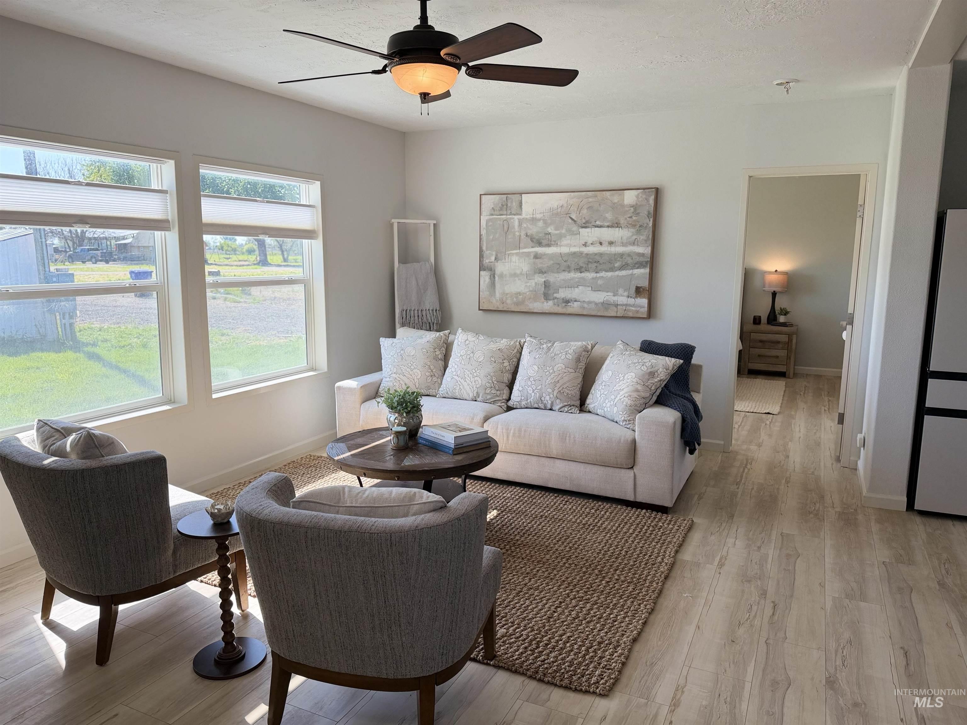 875 Eaton Road Weiser, ID 83672 - Photo 9 of 30 Spacious living area featuring light-toned wood-finish flooring, a ceiling fan with integrated lighting, and multiple windows