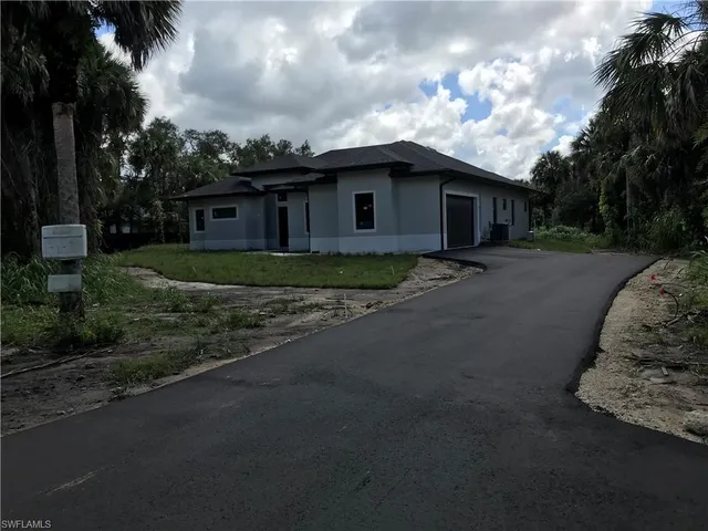a view of a house with a yard plants and a large tree