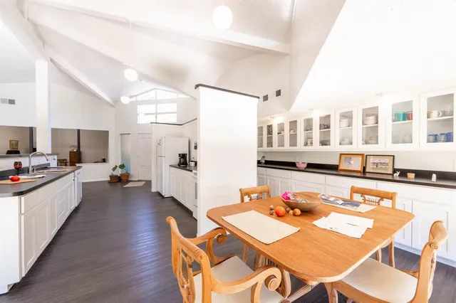 a living room with stainless steel appliances furniture dining table and wooden floor