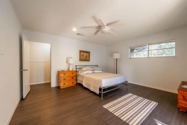 a spacious bedroom with a bed and wooden floor
