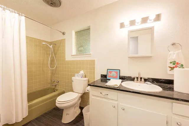 a bathroom with a granite countertop sink a toilet and shower