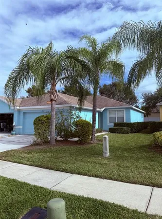 a front view of a house with a garden and palm trees