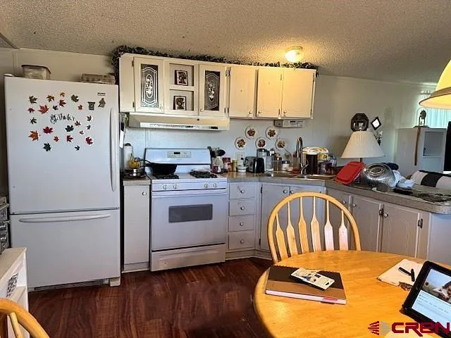 a open kitchen with granite countertop a stove a sink dishwasher and white cabinets with wooden floor