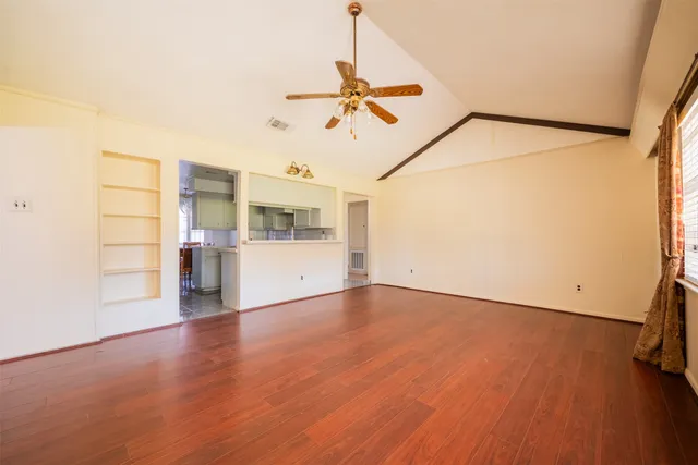 an empty room with a chandelier fan and windows