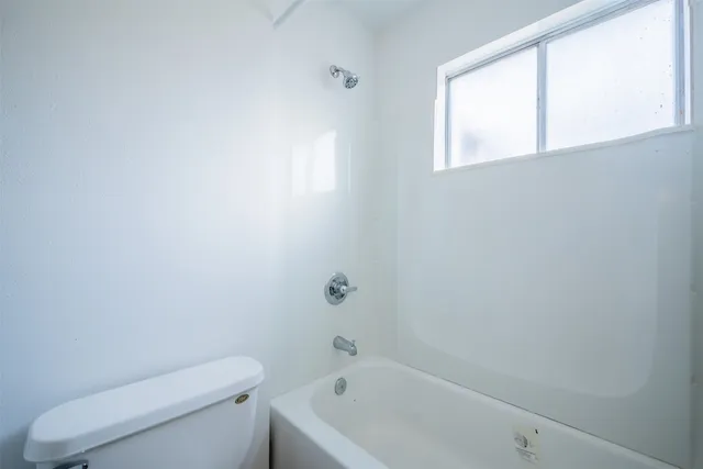 an empty room with a ceiling fan and window