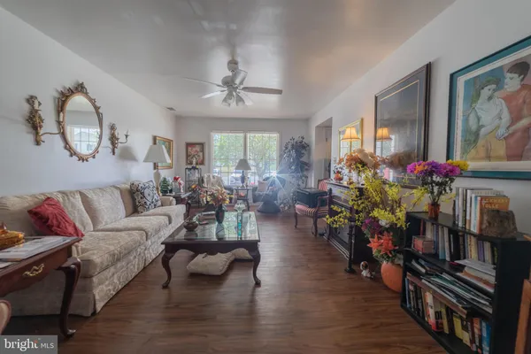 a living room with furniture flowers and wooden floor