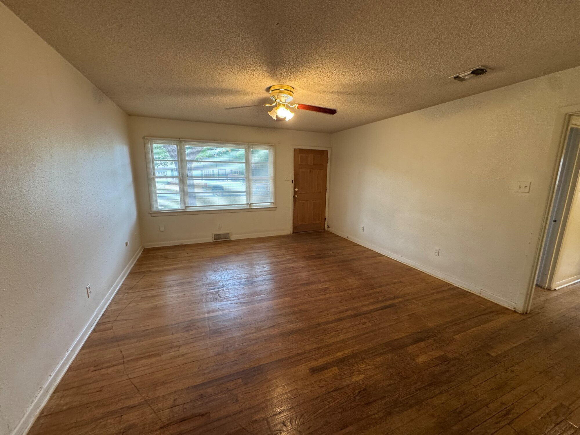 3709 23rd Street Lubbock, TX 79410 - Photo 2 of 8 an empty room with wooden floor and windows