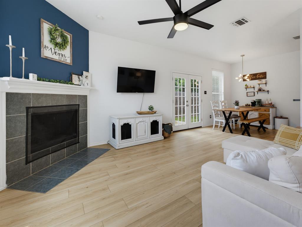 600 Stirling Road Rhome, TX 76078 - Photo 12 of 38 Living area featuring wood-finish flooring, a fireplace with a tiled surround, white mantel, and a contrasting blue accent wall