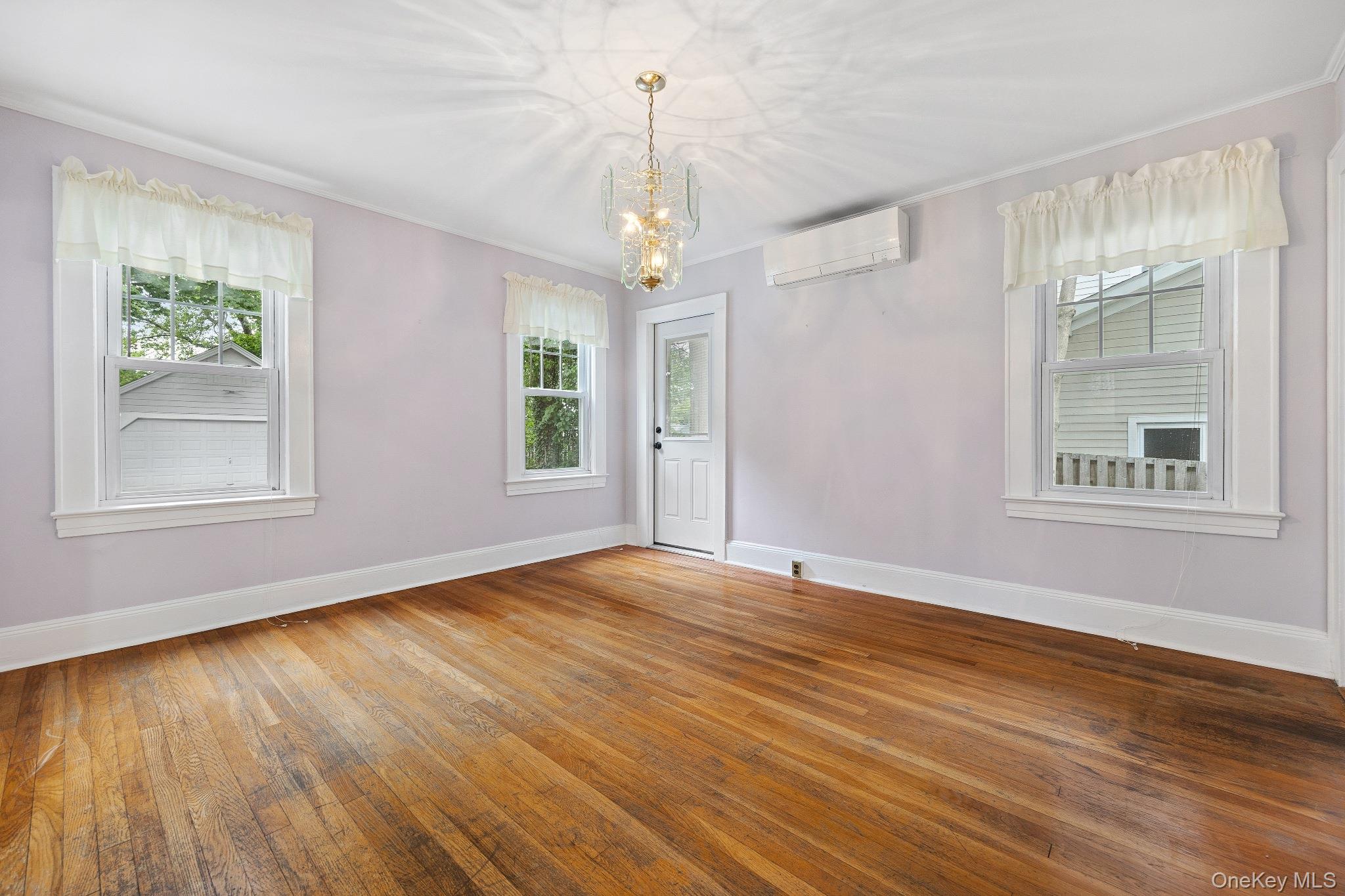 1235 Post Road Scarsdale, NY 10583 - Photo 11 of 30 Spare room with an AC wall unit, a chandelier, plenty of natural light, hardwood / wood-style floors, and crown molding