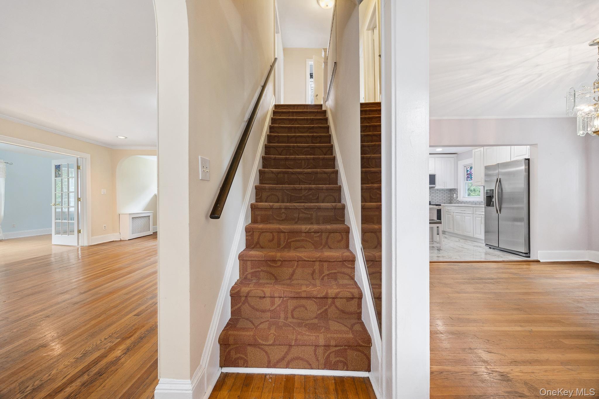 1235 Post Road Scarsdale, NY 10583 - Photo 15 of 30 Staircase featuring arched walkways, crown molding, wood finished floors, and a chandelier