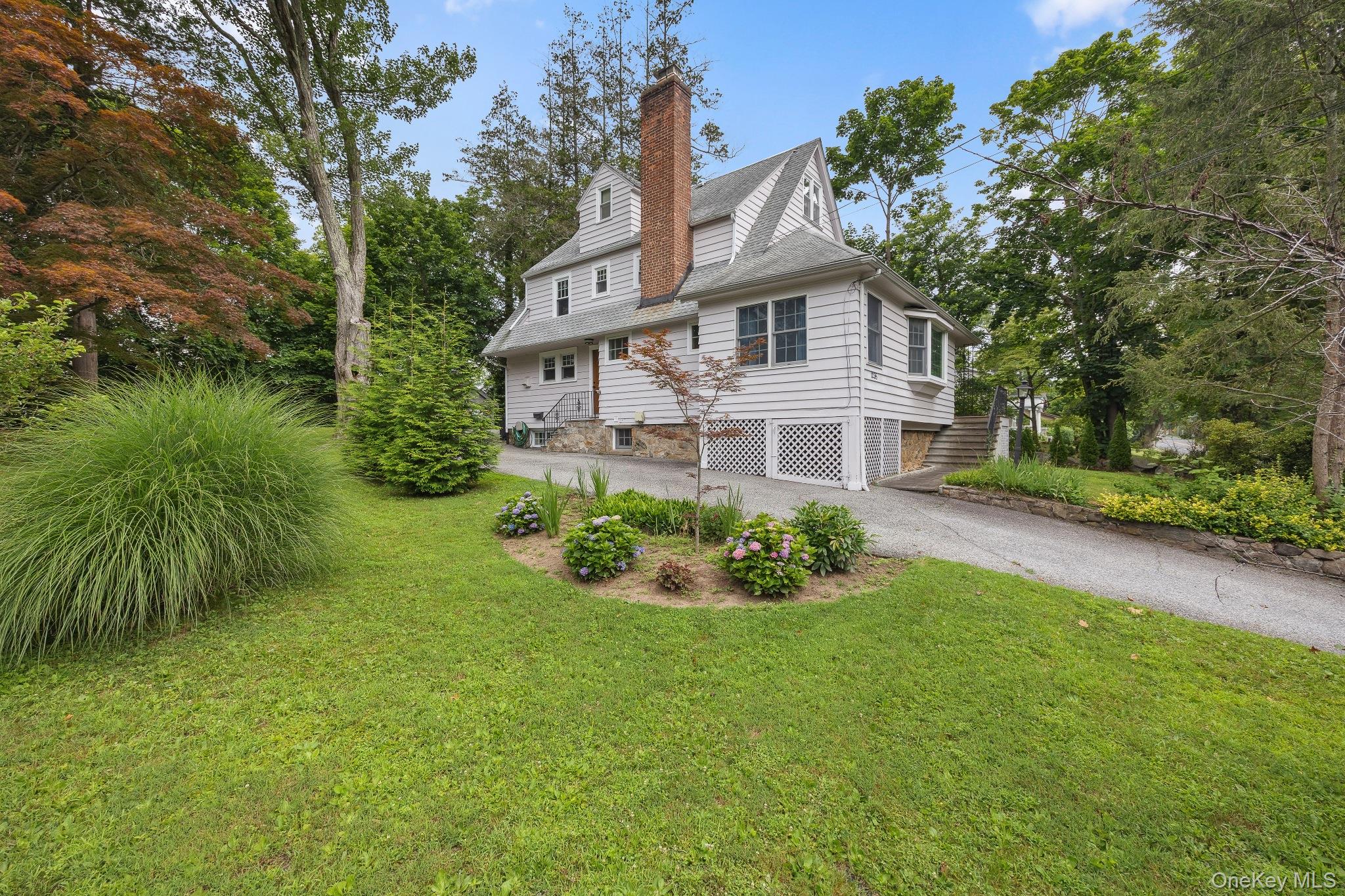 1235 Post Road Scarsdale, NY 10583 - Photo 2 of 30 View of side of home with a chimney, asphalt driveway, a lawn, and stairway