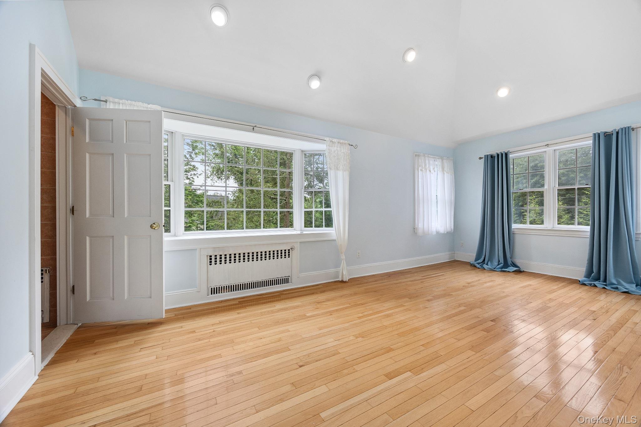 1235 Post Road Scarsdale, NY 10583 - Photo 7 of 30 Spare room featuring radiator heating unit, healthy amount of natural light, hardwood / wood-style floors, lofted ceiling, and recessed lighting