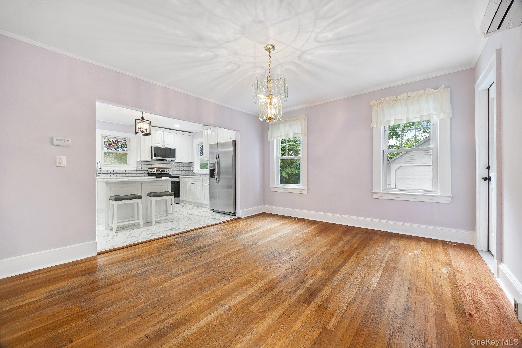 1235 Post Road Scarsdale, NY 10583 - Photo 10 of 30 Unfurnished living room featuring light wood-style flooring, crown molding, a chandelier, and a wall mounted AC