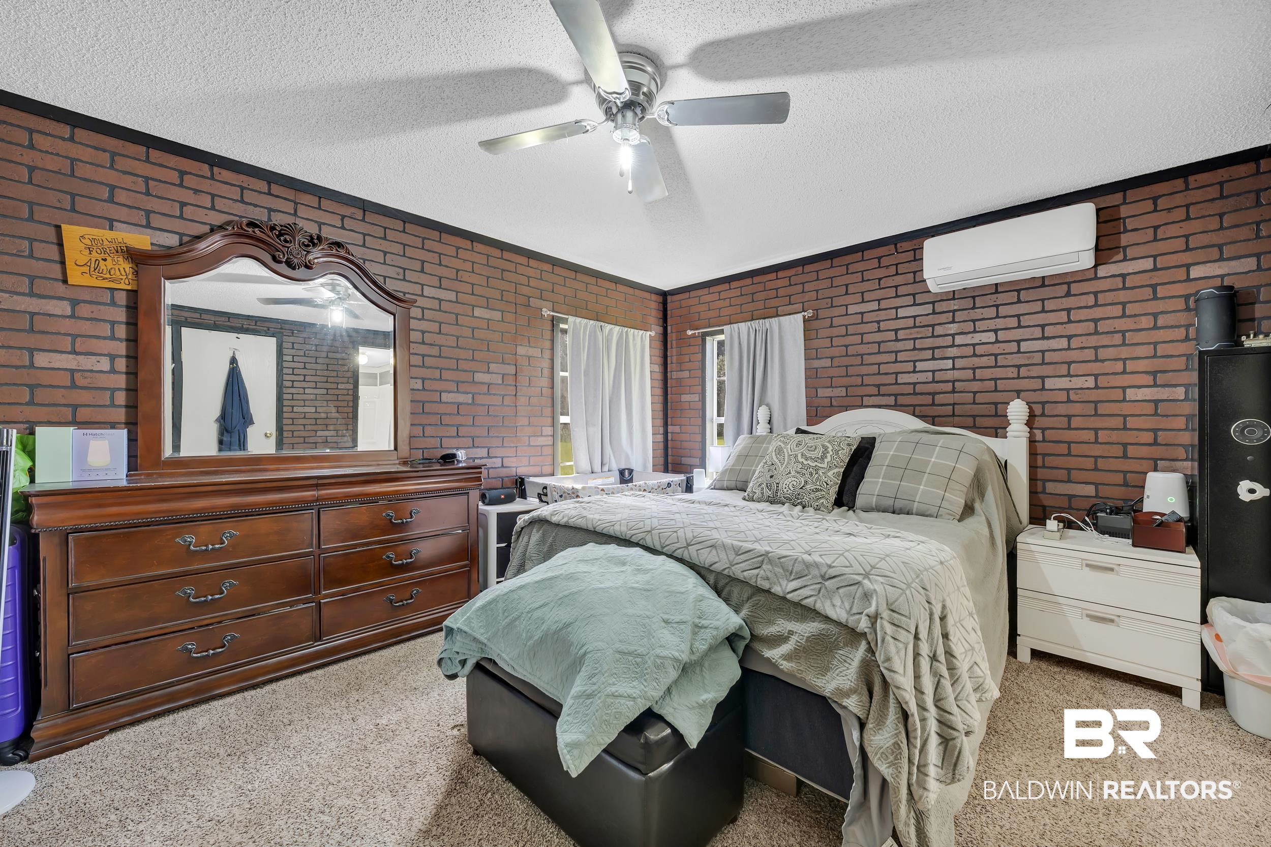 22823 Lanier Road Robertsdale, AL 36567 - Photo 45 of 46 Bedroom with light carpet, a textured ceiling, ceiling fan, a wall mounted air conditioner, and brick wall