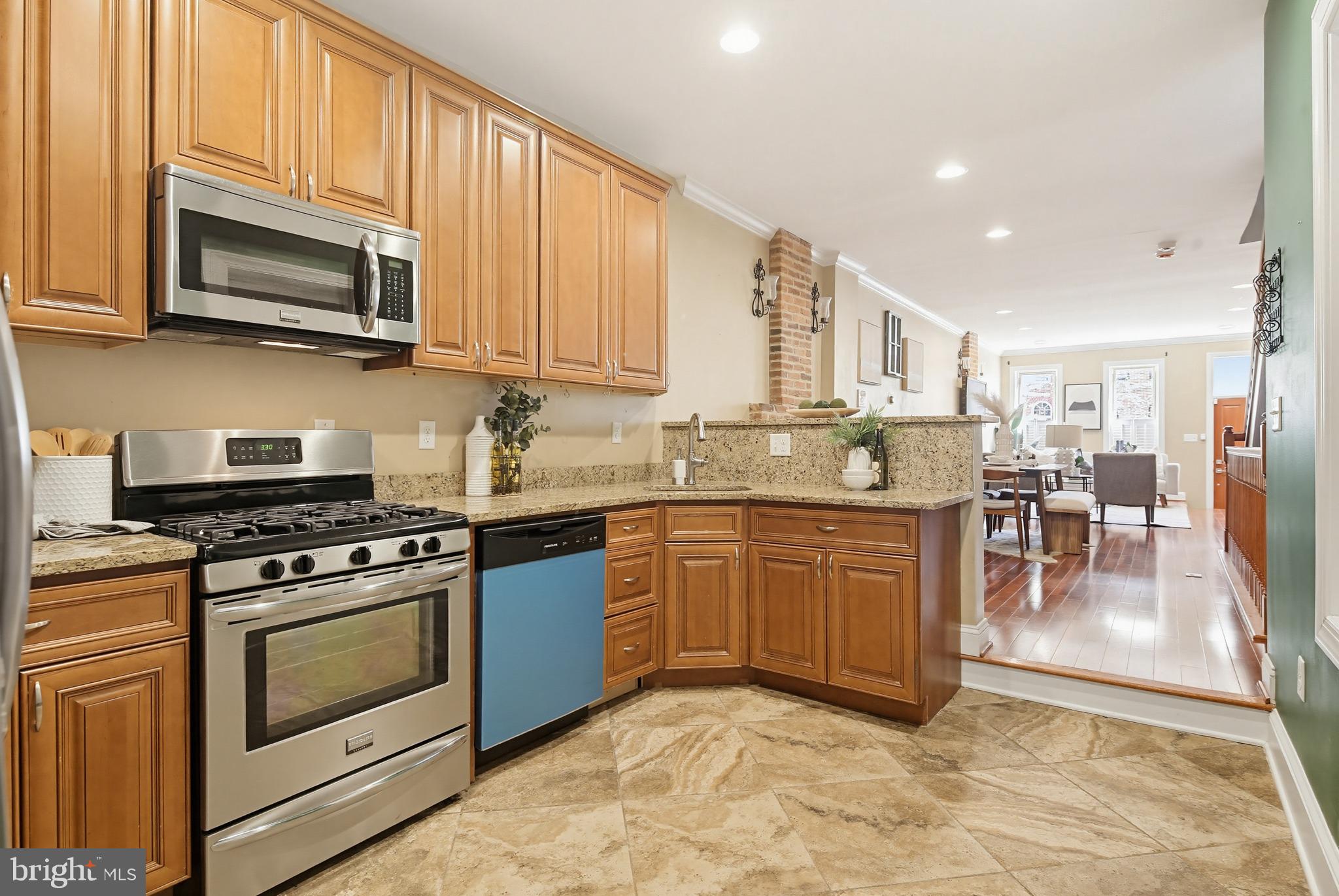122 West Clement Street Baltimore, MD 21230 - Photo 11 of 40 a kitchen with stainless steel appliances granite countertop a stove top oven a sink dishwasher a dining table and chairs with wooden floor