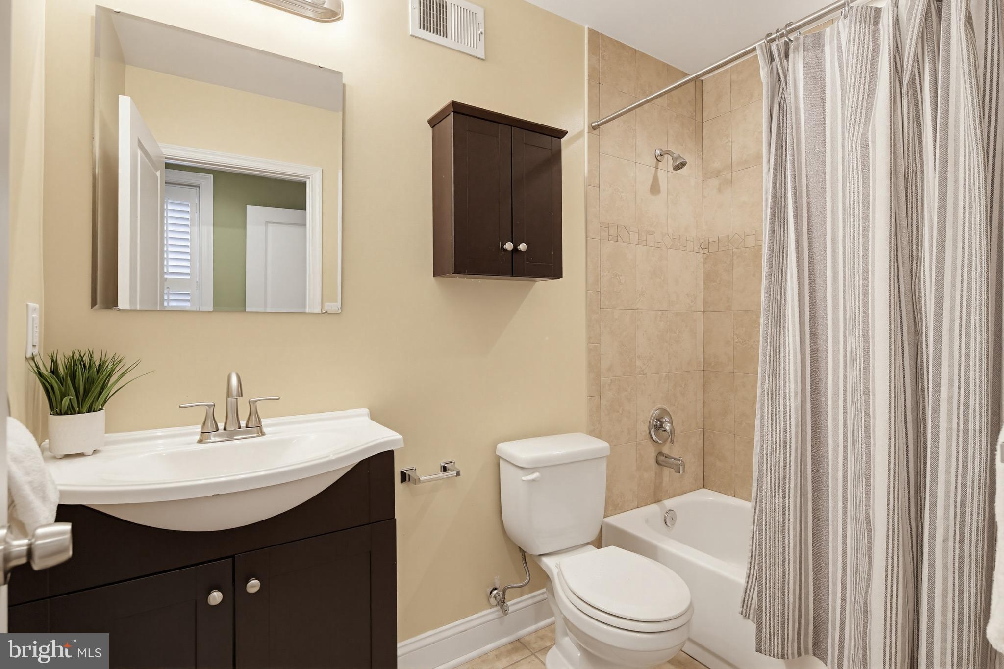 122 West Clement Street Baltimore, MD 21230 - Photo 21 of 40 a bathroom with a sink a toilet a mirror and shower curtain