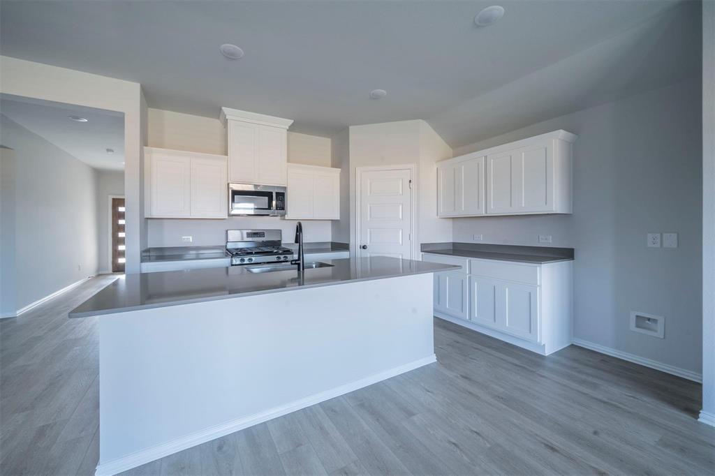 516 Ridgewood Drive Van Alstyne, TX 75495 - Photo 8 of 25 Kitchen featuring a center island, white cabinetry, integrated stainless steel appliances, and wood-finish flooring