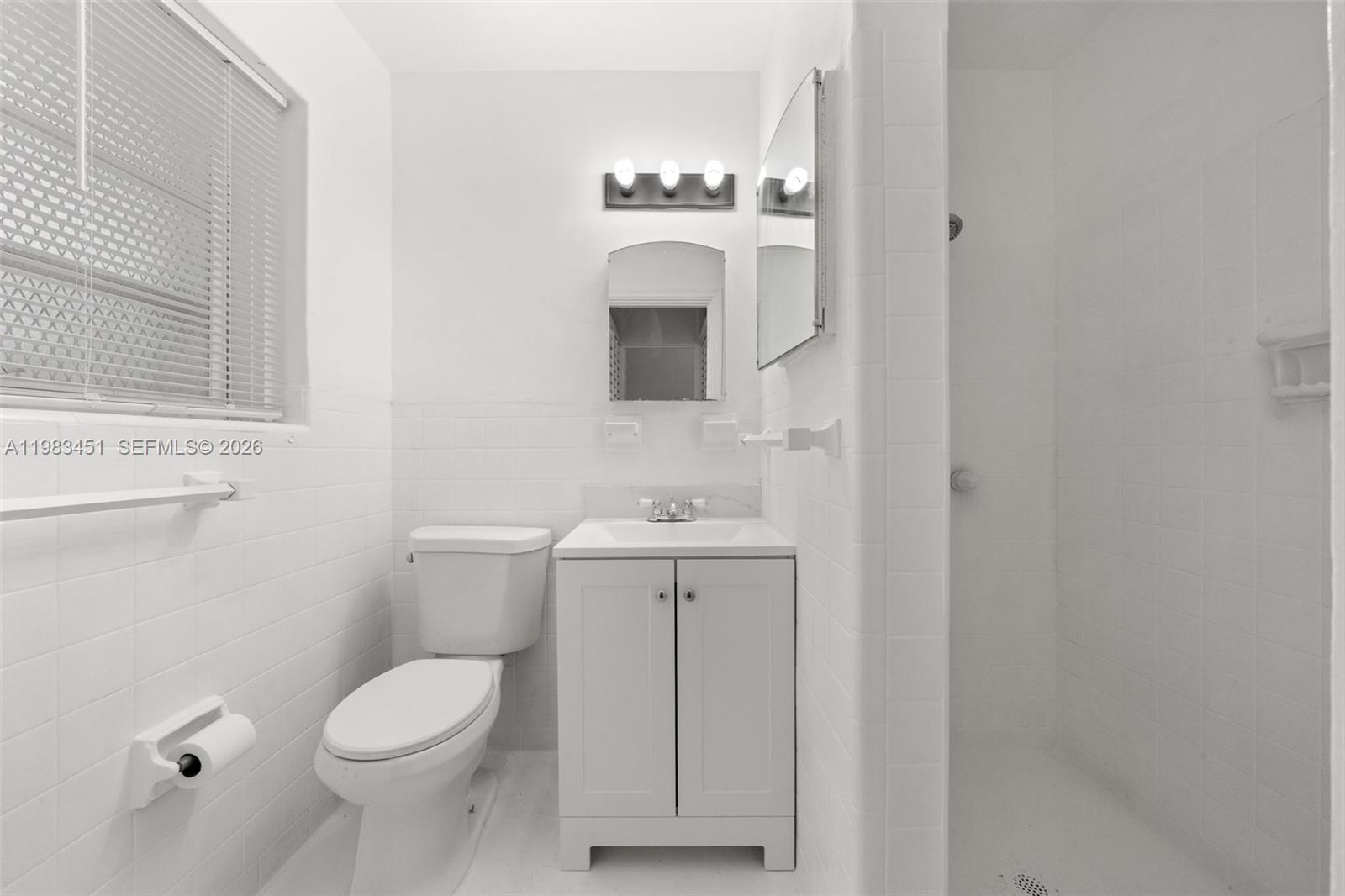 840 Southwest 7th Street, Unit 850 Miami, FL 33130 - Photo 4 of 12 a bathroom with a toilet a sink and mirror