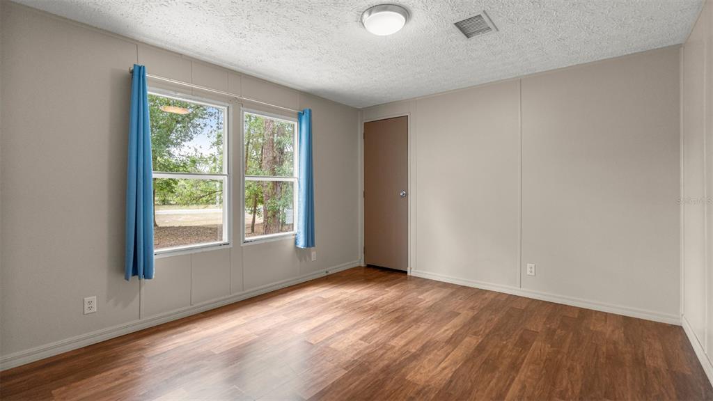 10379 Southwest 135 Street Archer, FL 32618 - Photo 22 of 45 an empty room with wooden floor and windows