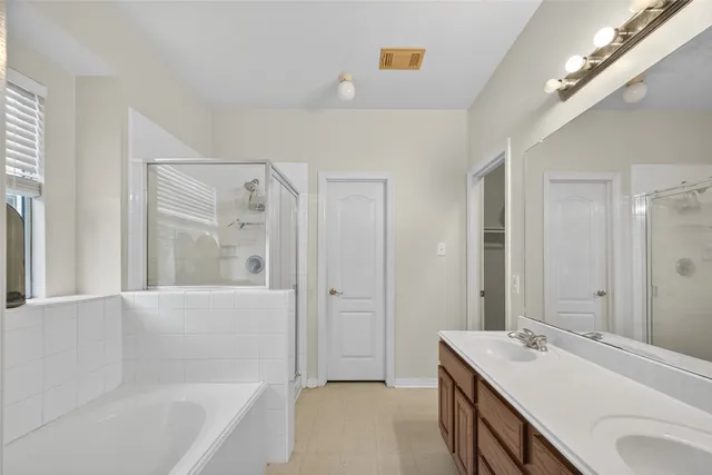 a bathroom with a sink double vanity granite tub shower and a mirror
