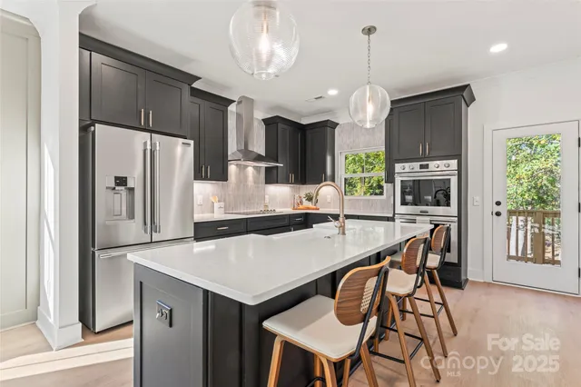 a kitchen with stainless steel appliances a dining table chairs refrigerator and microwave