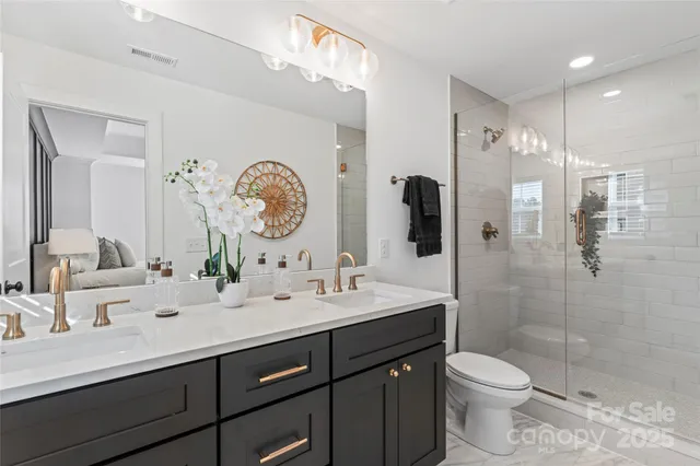 a bathroom with a double vanity sink toilet mirror and shower