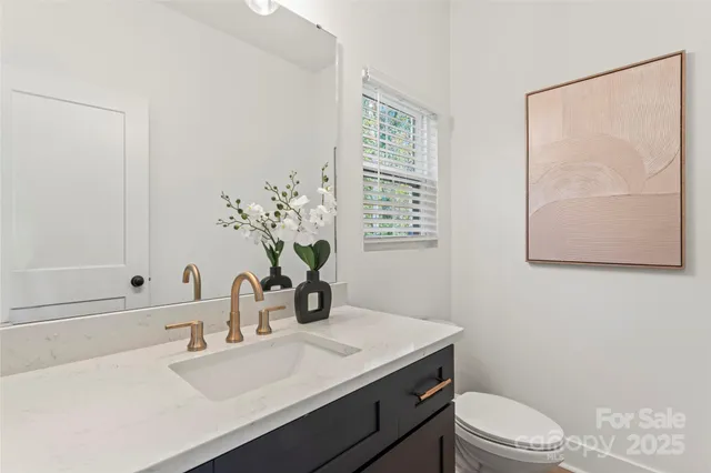 a bathroom with a granite countertop sink a toilet and mirror