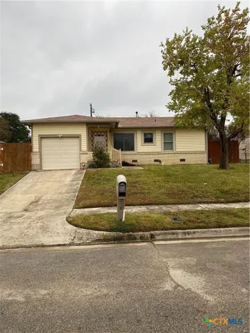 a view of a house with a yard and large tree