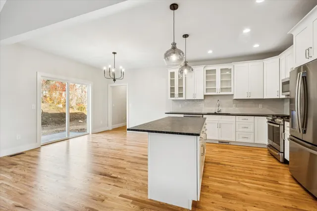 a kitchen with stainless steel appliances granite countertop a sink a stove and a wooden floors