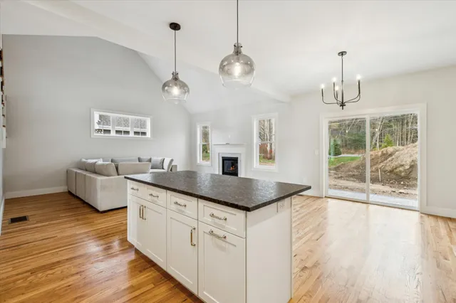 a kitchen with stainless steel appliances granite countertop a sink dishwasher a refrigerator and a dining table with wooden floor