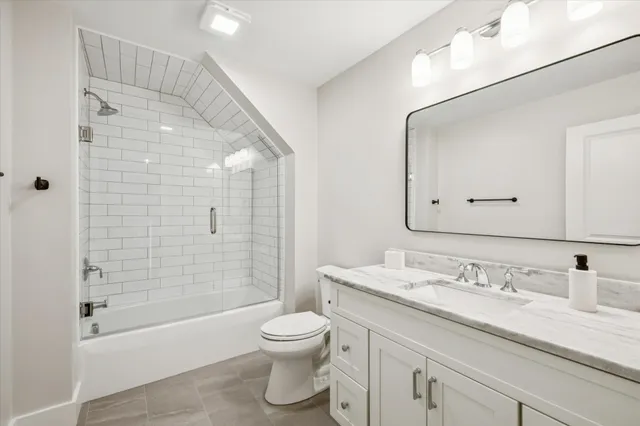 a bathroom with a granite countertop sink a toilet and shower